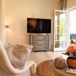 Wohnzimmer mit Fernseher, Schrank und Terrassentür. Tisch mit Blumen und Kerze.