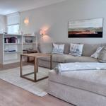 Ein Wohnzimmer mit grauem Sofa, Holztisch und Wandbild.