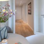 Tisch mit Donuts und Blumen, Blick in einen Flur mit Holzboden und Wandbild.