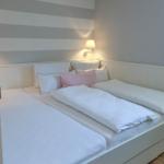 Schlafzimmer mit Doppelbett, gestreifter Wand und Wandlampe.