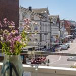 Balkon mit Blumen und Obst, Blick auf Straße und Gebäude.