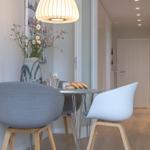 Essbereich mit Tisch, Stühlen und Deckenleuchte. Hintergrund: Flur mit Tür.