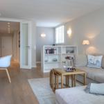 Wohn- und Essbereich mit Sofa, Tisch und Bücherregal. Holzboden und moderne Einrichtung.