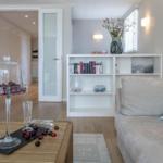 Wohnzimmer mit Sofa, Bücherregal und Tisch mit Kirschen unter Glas.