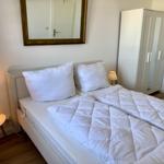 Schlafzimmer mit Bett, Nachttisch, Spiegel und Kleiderschrank.