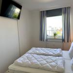 Zimmer mit Doppelbett, Fenster mit Blick und Wand-TV.
