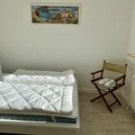 Schlafzimmer mit Bett, Stuhl und Wandbild von VW-Bussen.