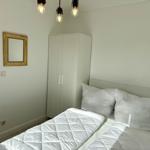 Schlafzimmer mit weißem Bett, Kleiderschrank und Spiegel an der Wand.