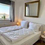 Schlafzimmer mit Doppelbett, Fenster, Spiegel und Nachttischlampen.