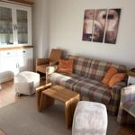 Wohnzimmer mit Sofa, Sessel und Tisch. An der Wand hängt ein Bild.