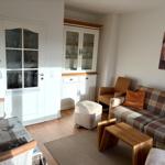 Wohnzimmer mit Sofa, Sessel und Esstisch. Hintergrund: Fenster und Schrank.
