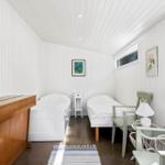 Two beds, a dresser, chairs, and windows in a room with white walls.
