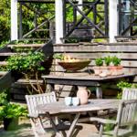 Wooden table with chairs, fire bowl, and plants on terrace.