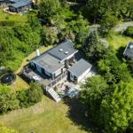 House with terrace, garden, and trampoline surrounded by trees.