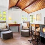 Living room with fireplace, two chairs, and view to balcony.