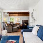 Living room with sofa, armchairs, and fireplace. Wooden floor and white walls.
