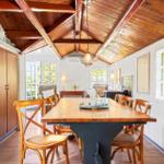 Dining room with wooden table, chairs, and high ceiling with beams.