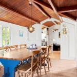 Dining area with wooden table, chairs, and view into the kitchen.