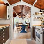 Kitchen with wooden surfaces and view into dining room with blue table.