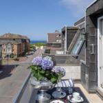 Balcony with table, flowers, and sea view.