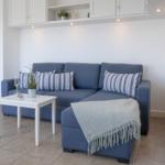 Ein Wohnzimmer mit blauem Sofa, weißen Schränken und einem kleinen Tisch.