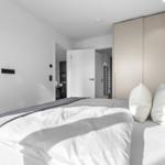 Schlafzimmer mit Bett, Kleiderschrank und Sicht in angrenzende Räume.