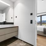 Badezimmer mit Waschtisch und Spiegel. Schlafzimmer mit Bett und Fenster.