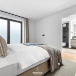 Schlafzimmer mit Bett, Fenster und Blick in das Badezimmer.