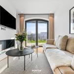 Wohnzimmer mit Sofa, Fernseher und Blick auf die Terrasse.