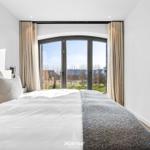 Schlafzimmer mit großem Bett und Bogenfenster zur Außenterrasse.