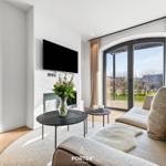 Wohnzimmer mit Sofa, TV und Blick auf die Terrasse.
