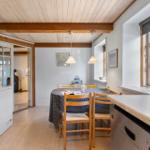 Kitchen with dining area, wooden ceiling, and window. Refrigerator, sink, and dining table with chairs.