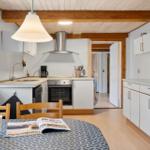 Kitchen with dining area, white cabinets, and wooden beams on ceiling.