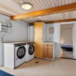 Laundry room with washer and dryer, wooden beam ceiling, view into bedroom.