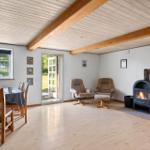 Room with wooden floor, fireplace, and recliners. Windows and door lead outside.