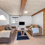 Living room with two sofas, table, TV, and door to outdoor area.