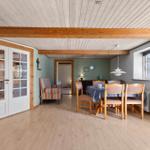Dining room with wooden table, chairs, and window. Stairs and door in the background.