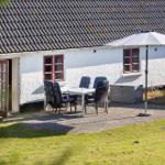 House with terrace, table, chairs, and umbrella. White exterior wall and red windows.