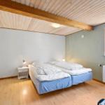 Room with double bed, wooden ceiling, and window. A nightstand is next to the bed.