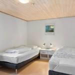 Two beds with white bedding, nightstand with lamps and picture on the wall.