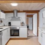 Kitchen with white cabinets, stainless steel sink, and oven under wooden ceiling.