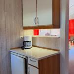 Küchenbereich mit Kühlschrank, Kaffeemaschine und Holzschränken.