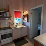 Küche mit Herd, Spüle und Fenster. Tür führt in Schlafzimmer.