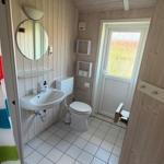 Bad mit Dusche, Waschbecken und Toilette. Holzwände und Fliesenboden.