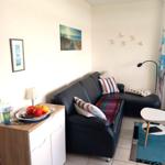 Wohnzimmer mit Sofa, Tisch und Wandbildern.