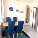 Esszimmer mit runder Tisch, blauen Stühlen und Wanduhr