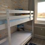 Zimmer mit Doppelstockbett und Fenster. Wandtapete mit Worten. Teppich auf dem Boden.