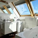 Badezimmer mit Dachfenster, Badewanne und Waschbecken.