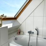 Bad mit Dusche und Dachfenster, weißer Fliesenwand und Waschbecken mit Vasen.