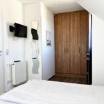 Schlafzimmer mit Bett, Kleiderschrank und Wandfernseher.